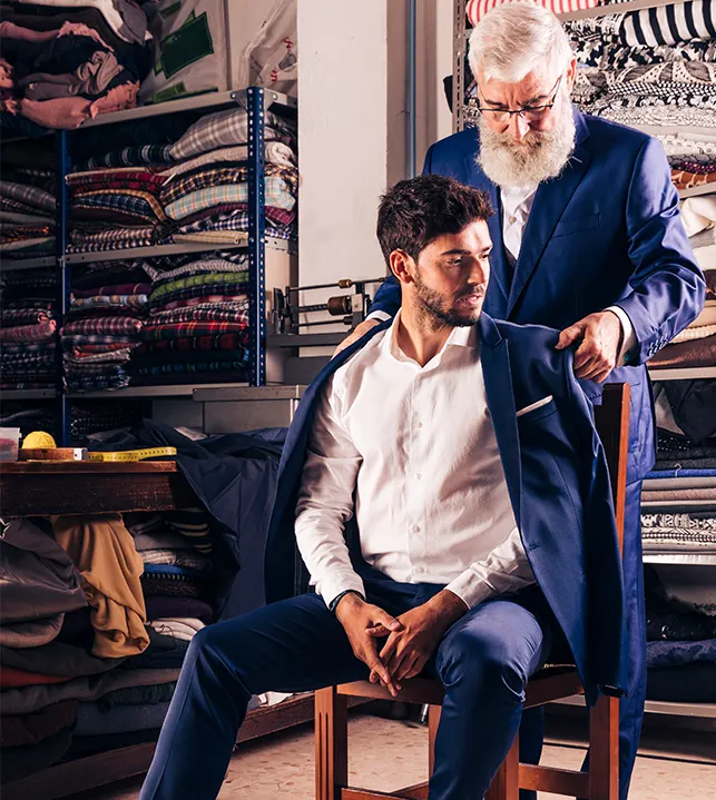 Tailor helping a customer with the fit of a navy suit jacket